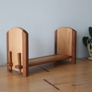 tabletop bookshelf with rounded top to the bookstands beside a plant