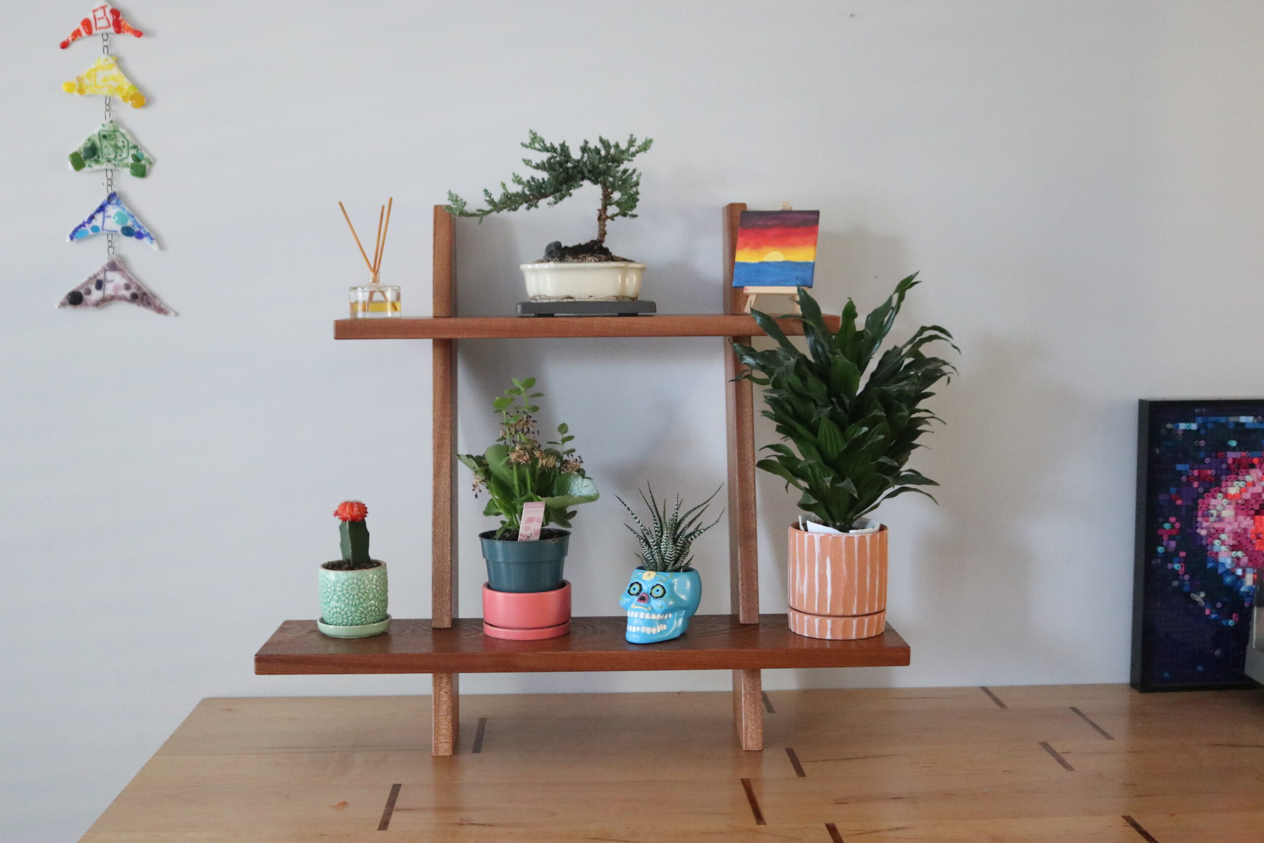 wooden plant stand with 2 shelves showing plants sitting on top of them